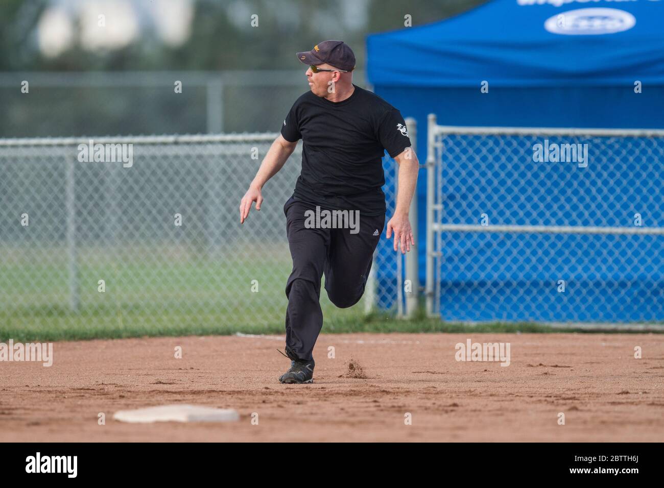 Playing in a mixed slo pitch softball game, male running to second base. Stock Photo