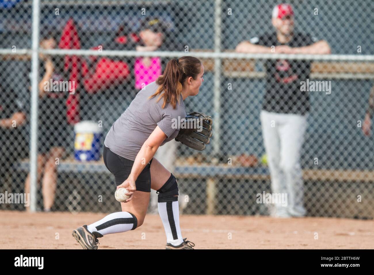 Playing in a mixed slo pitch softball game, female pitching Stock Photo