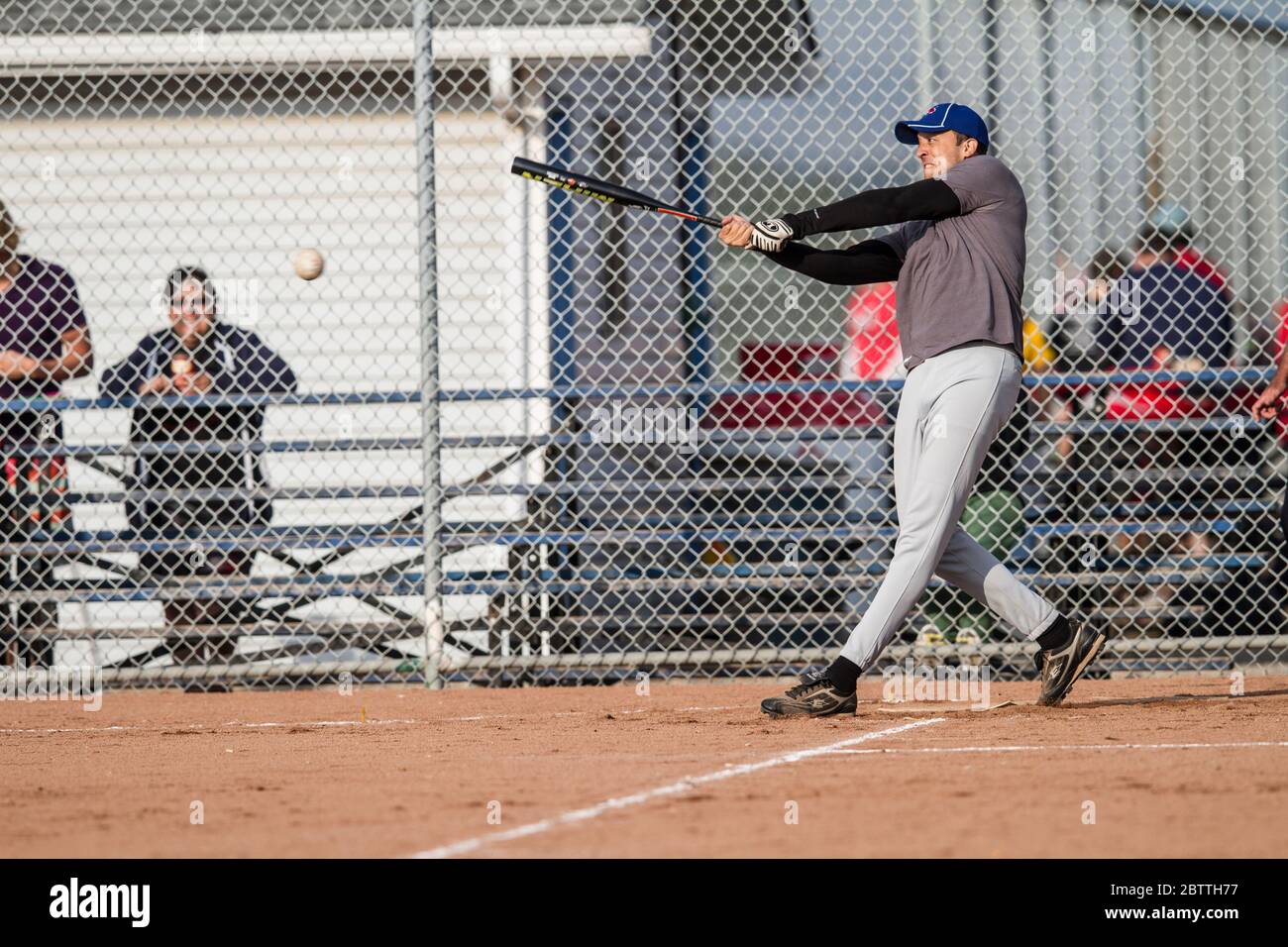 Playing in a mixed slo pitch softball game, male batting and hitting