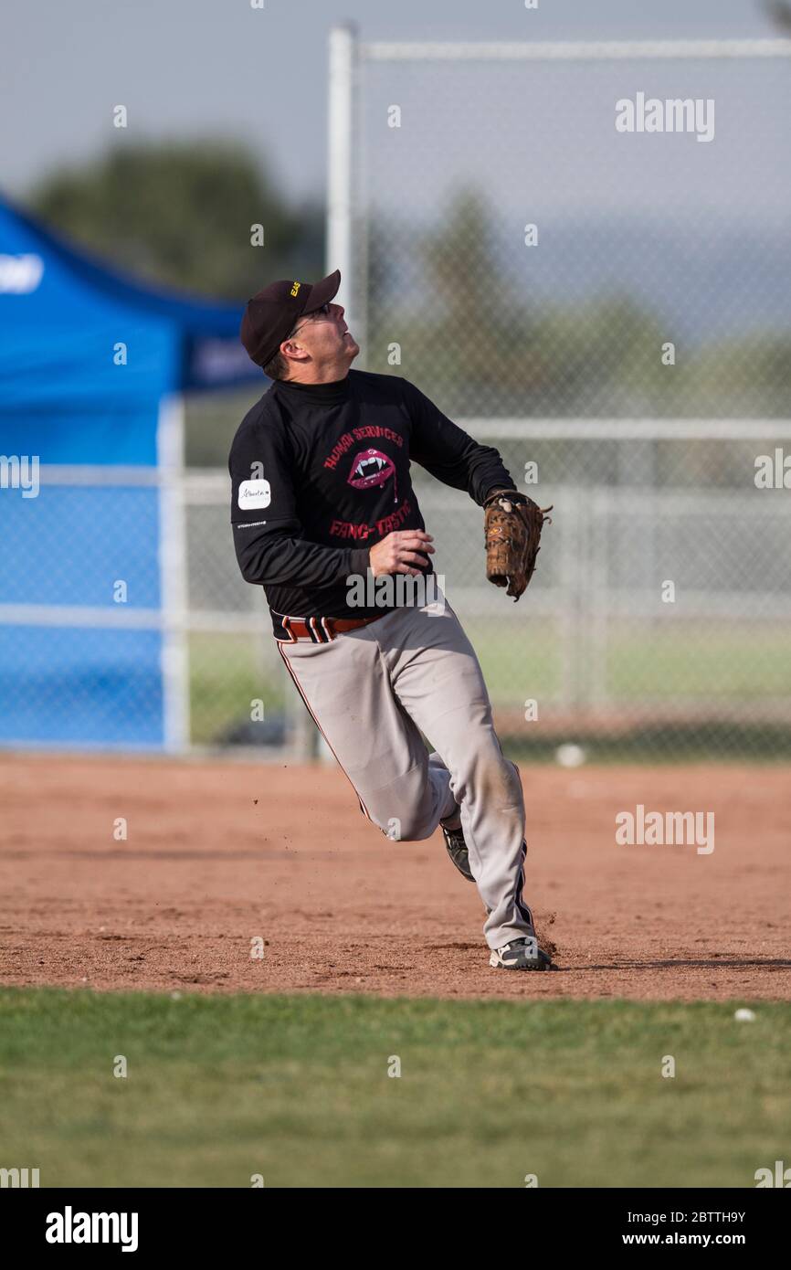 Playing in a mixed slo pitch softball game, male making a ground ball