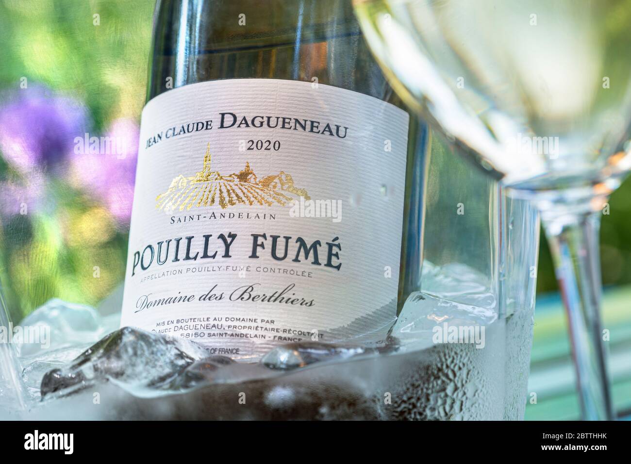 Pouilly Fume Sauvignon Blanc wine bottle and glass Jean-Claude Dagueneau 2020 post dated label in outdoor floral alfresco ice wine cooler Loire France Stock Photo