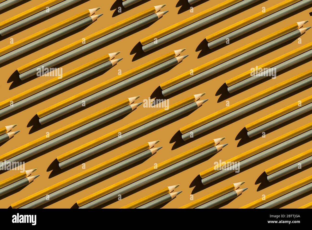Pattern of trendy gold and silver pencils on gold background. Back to school, education and learning concept. Minimal modern concept. Stock Photo