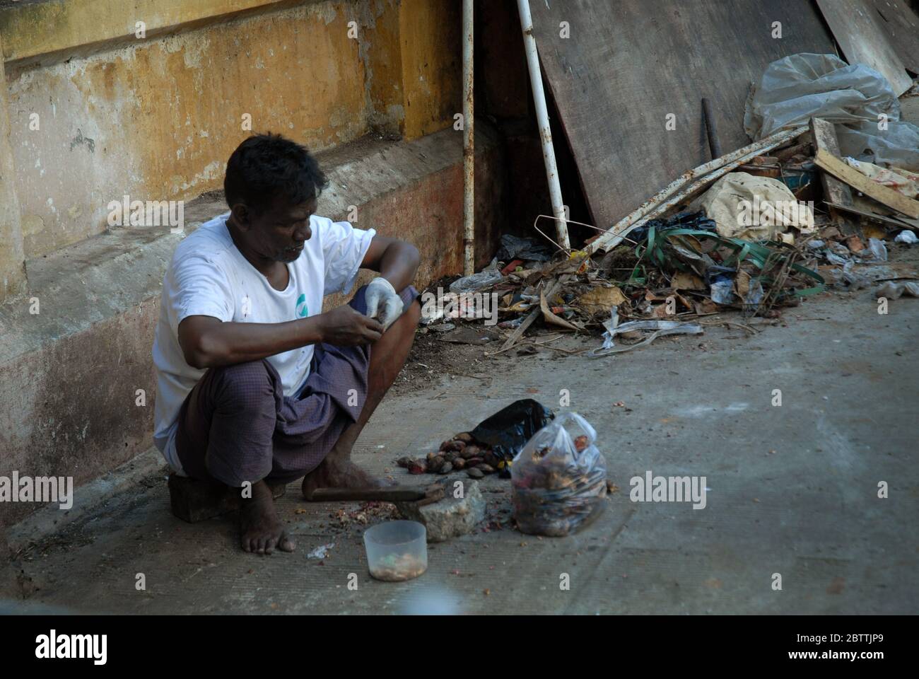Man cracking open betel nuts on the street in Yangon, Myanmar, Asia Stock Photo