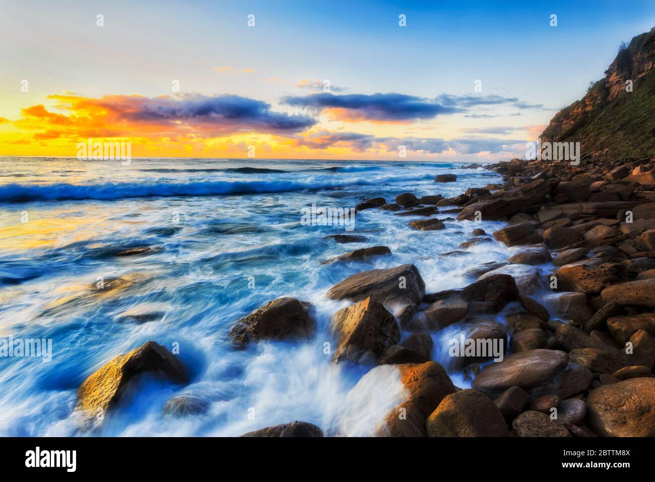 Round eroded rocks at Sydney Northern beaches washed by endless waves of Pacific ocean. Stock Photo
