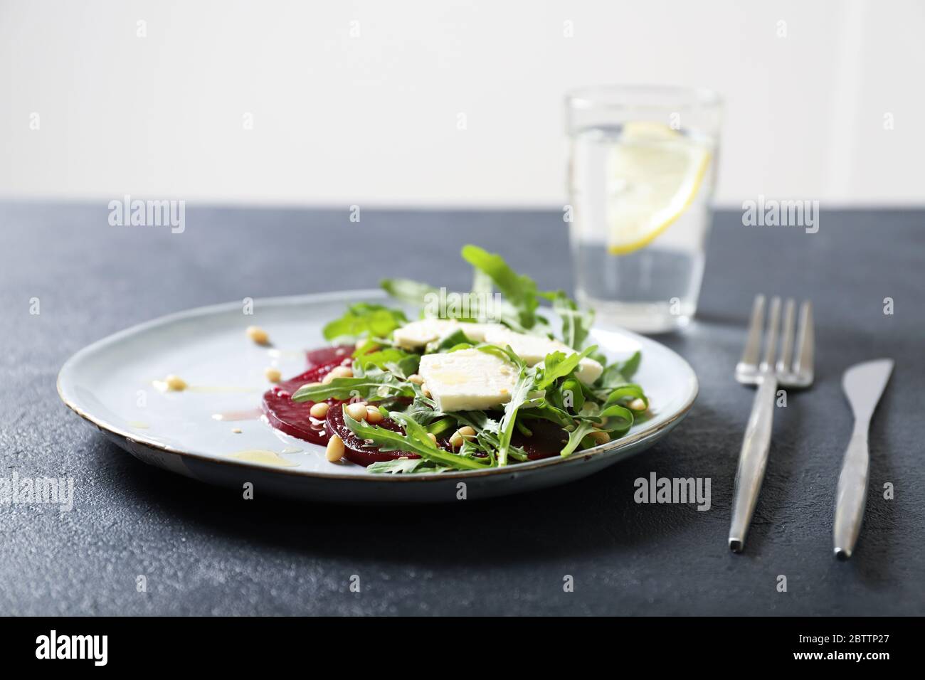 Plate with arugula, beet and feta salad. Sprinkled with pine nuts and honey Stock Photo