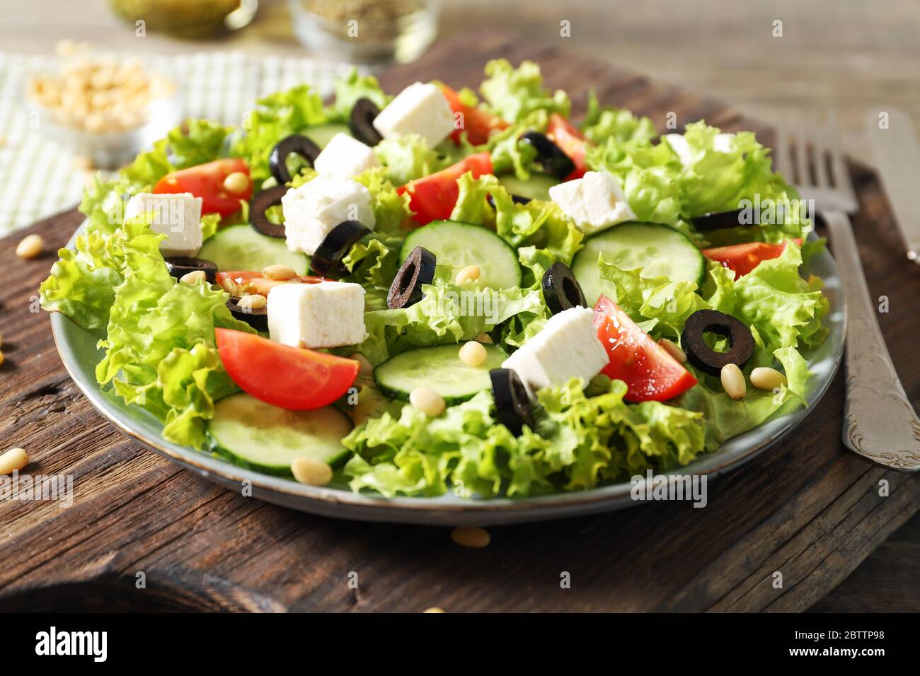Plate with tasty greek salad of fresh vegetables on wooden background Stock Photo