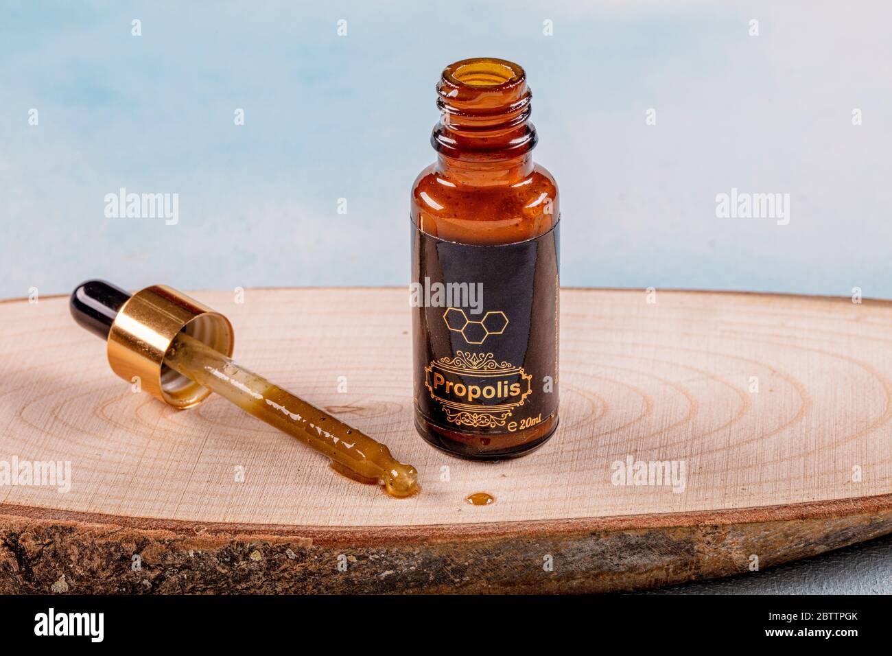 Propolis Drop Oil drop falling. A bottle of propolis on piece of wood. Stock Photo