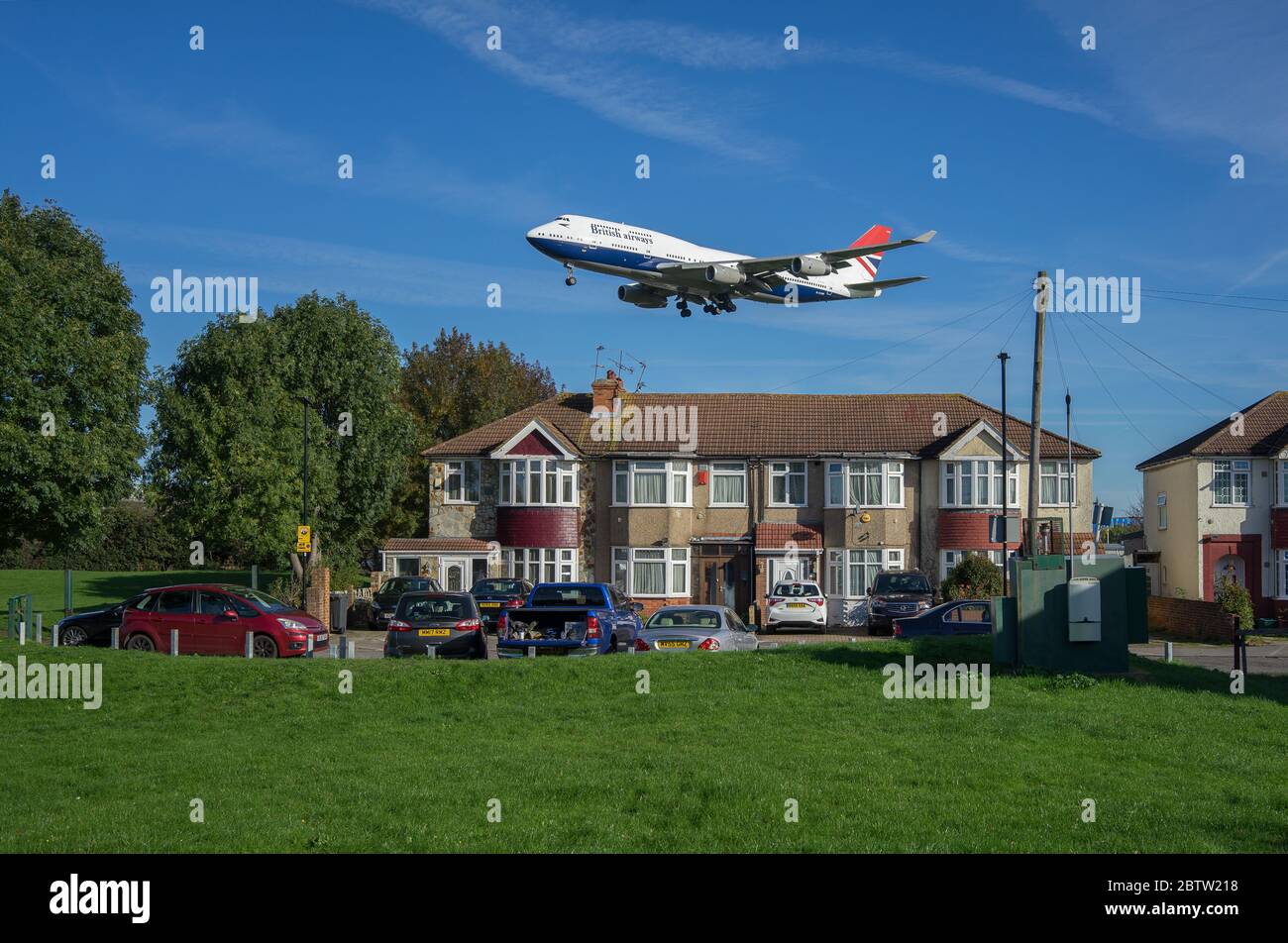 British Airways Boeing 747 landing at Heathrow Airport above residential houses on a sunny day with green grass in foreground. London. Stock Photo