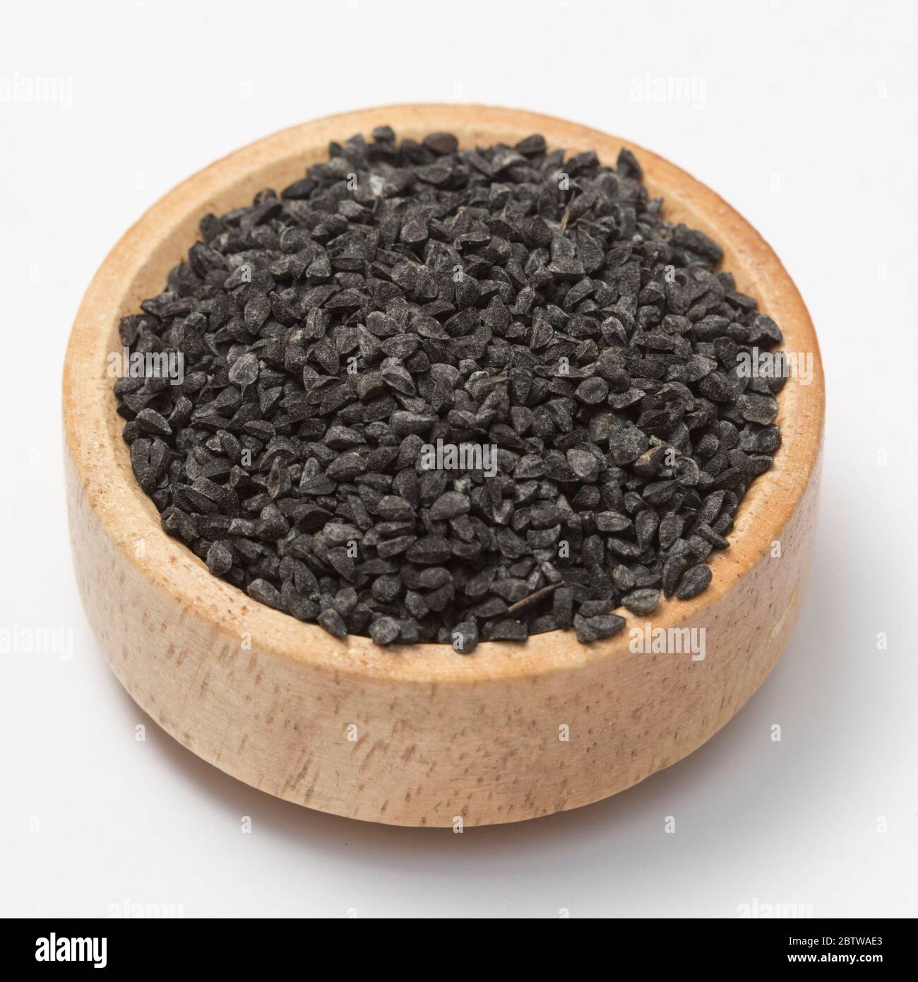 Close-up view of raw black cumins in a small wooden bowl on white background. Stock Photo