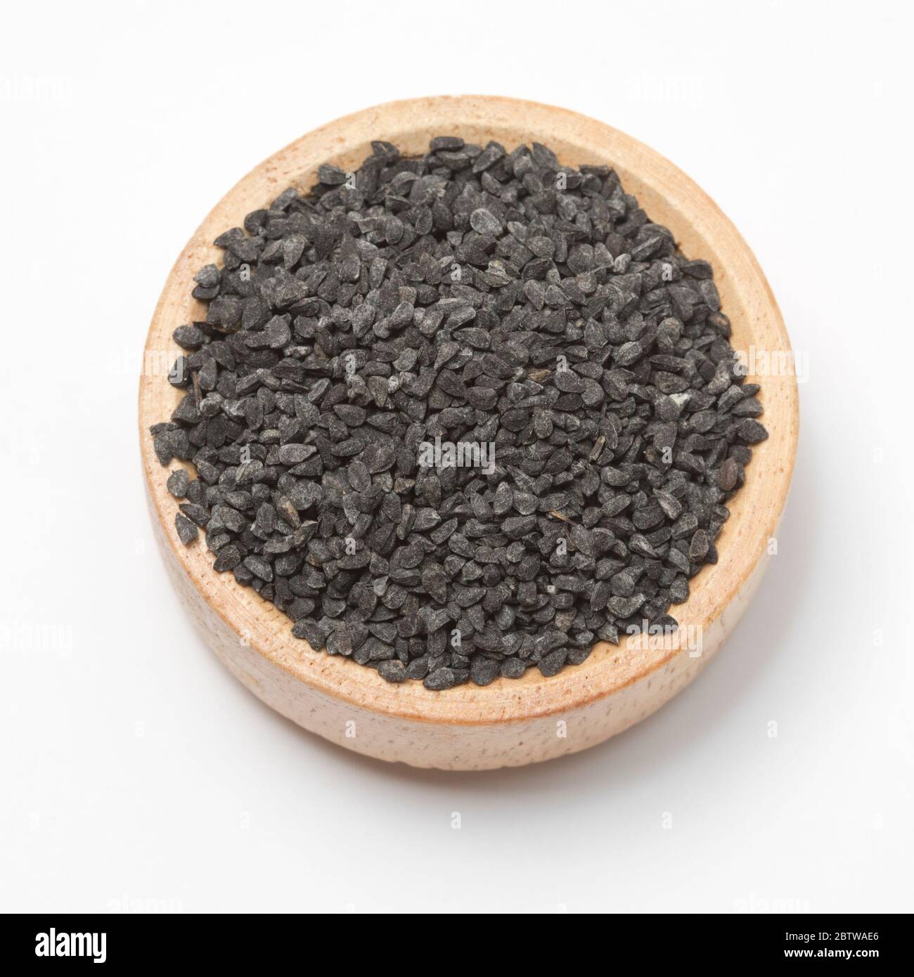 Close-up view of raw black cumins in a small wooden bowl on white background. Stock Photo