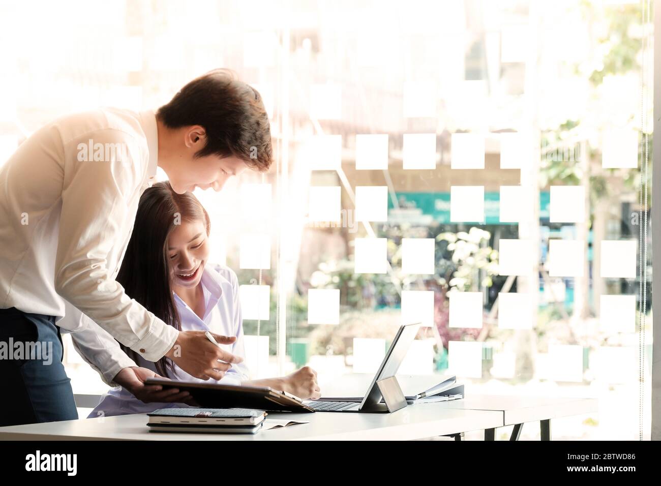 Two Young asian business partners working with financial papers and smart laptop Stock Photo