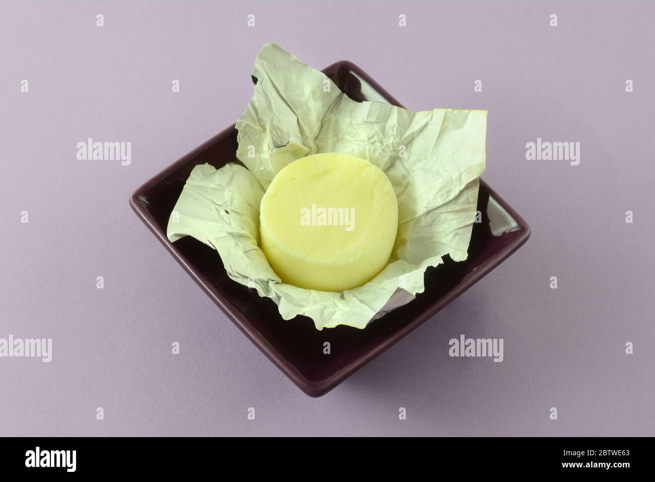 Individual portion of pad or pat of butter in foil wrapper in purple