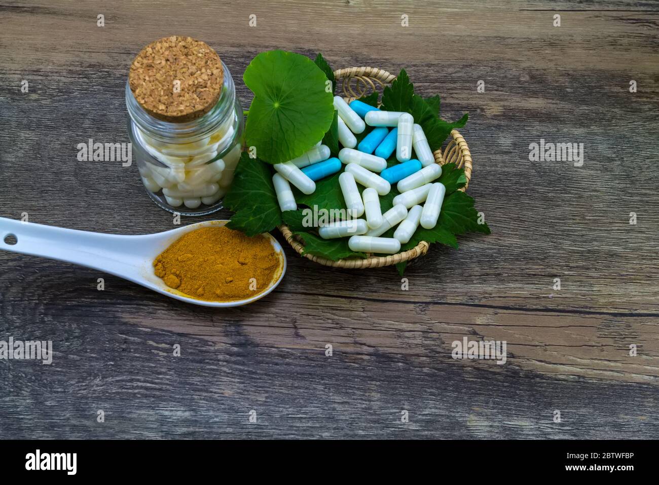 Colorful pill and yellow turmeric powder and green leaf of   White mugwort plant (Artemisia lactiflora) with Green Asiatic Pennywort (Centella asiatic Stock Photo