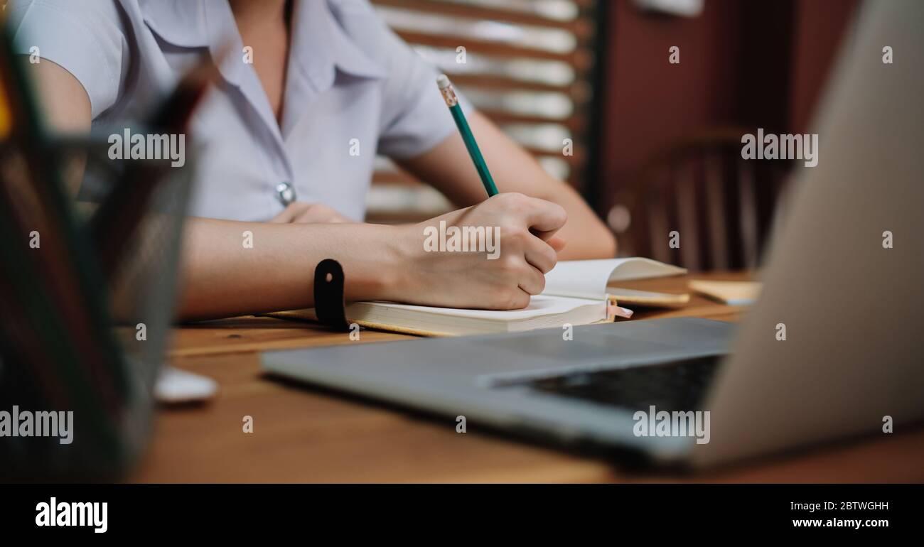 Close up student study online with teacher, young woman learn language listen lecture watch webinar write notes Stock Photo