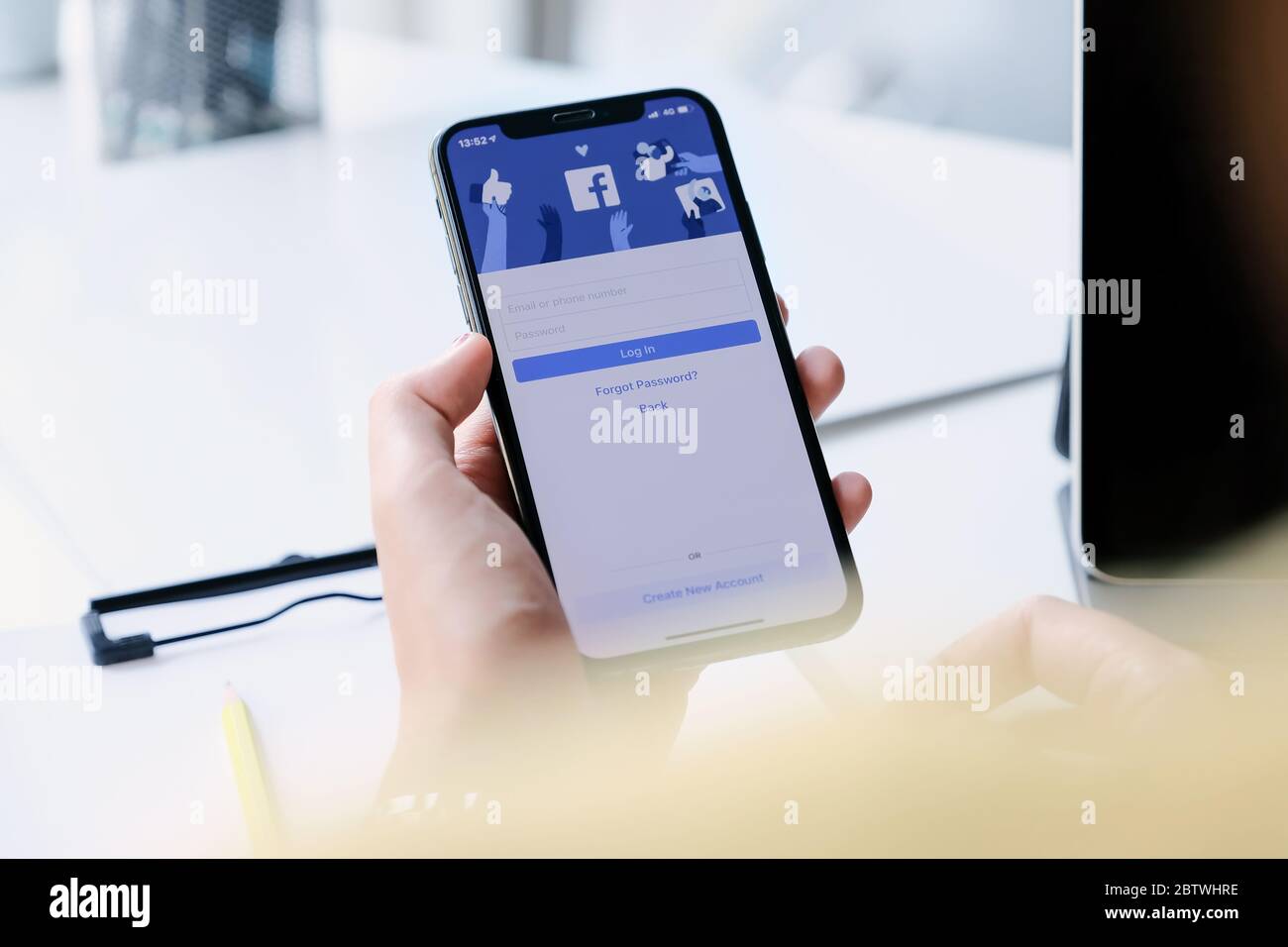 CHIANG MAI ,THAILAND - MAR 7, 2020 : Woman hand holding iPhone XS to use facebook with new login screen. Stock Photo