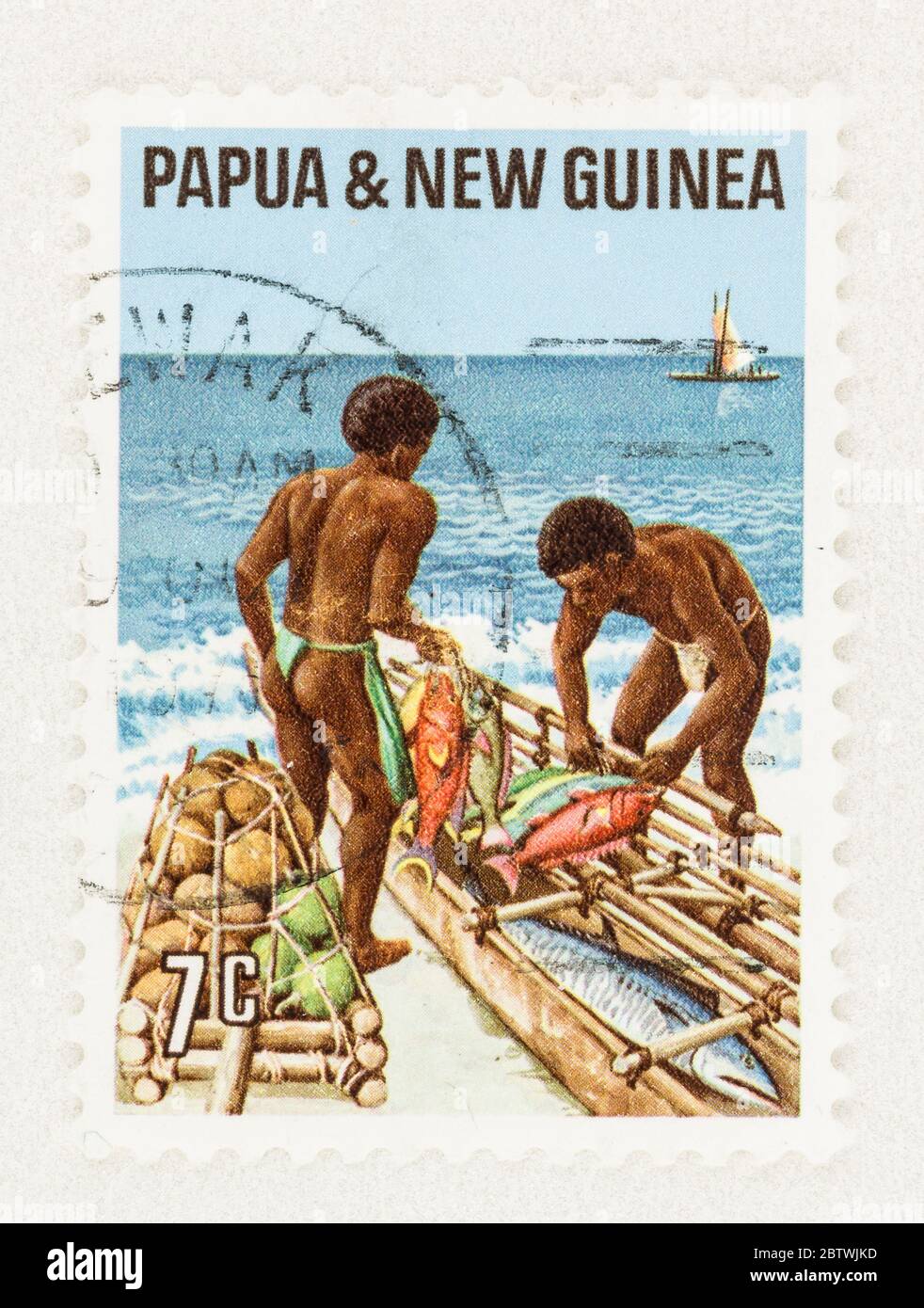 SEATTLE WASHINGTON - May 25, 2020:  Papua & New Guinea stamp featuring men on beach trading fish, coconuts and taro. Scott # 332 Stock Photo