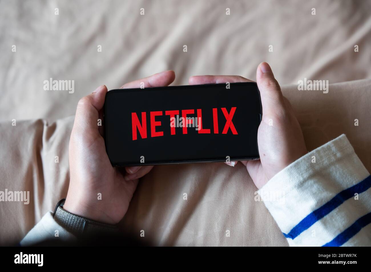 CHIANG MAI,THAILAND - APR 06, 2020 : Woman using iPhone X open Netflix application at home.  Stock Photo