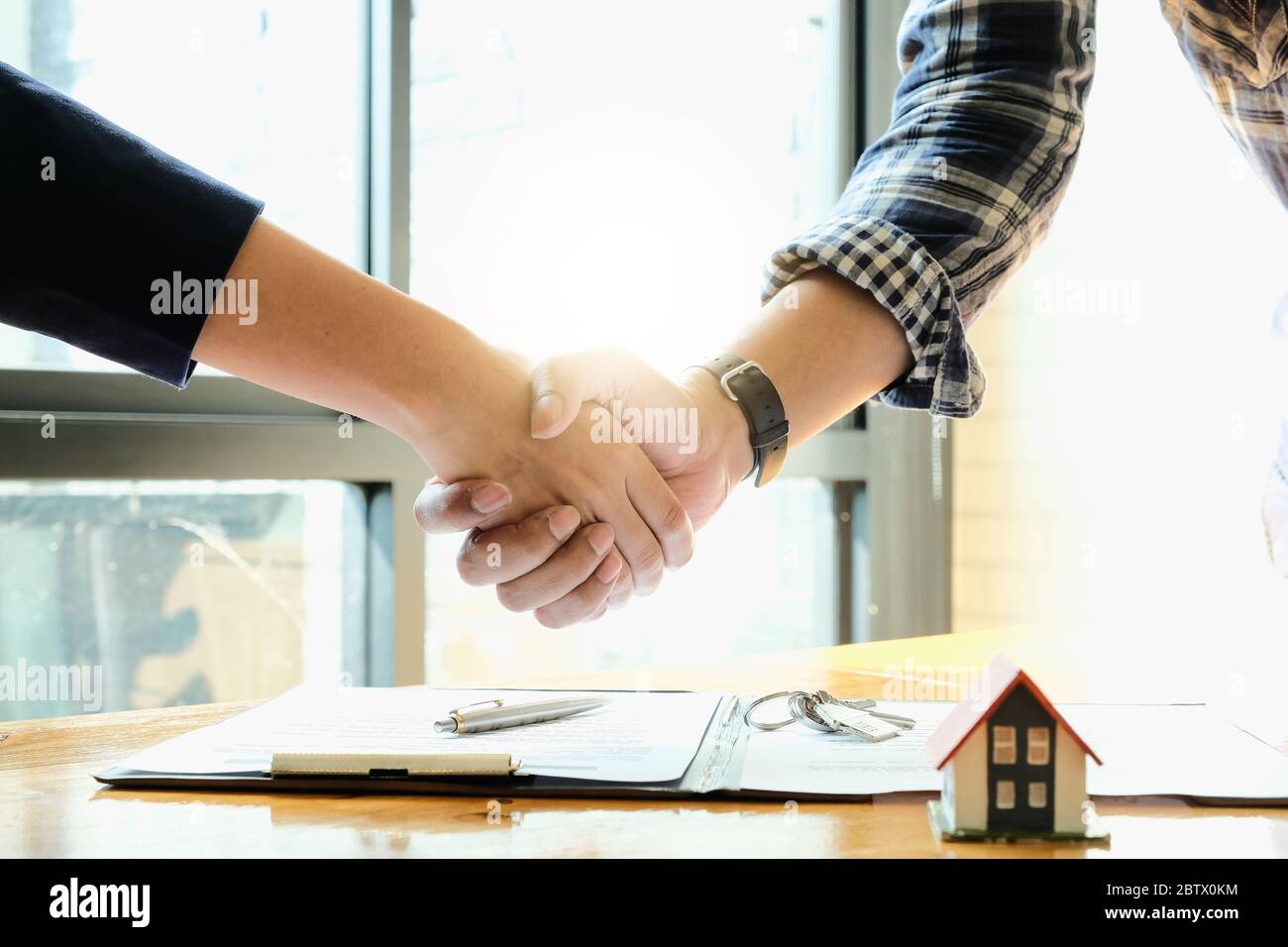 Real estate agent and customers shaking hands together celebrating