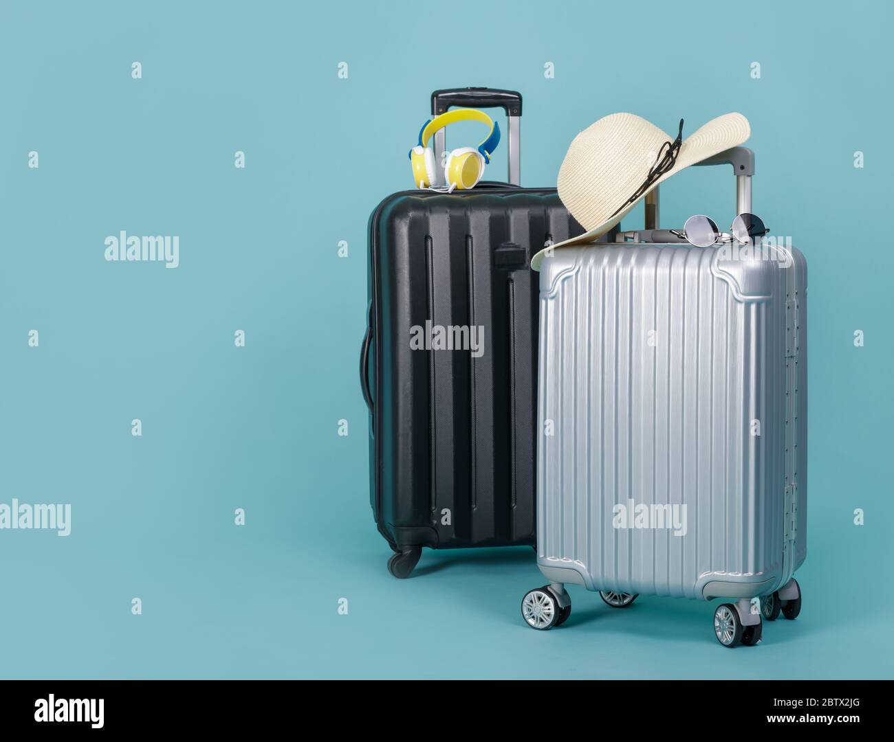 Two Travel Baggage with hat and sunglasses isolated on blue background with copy space, Travel concept background Stock Photo