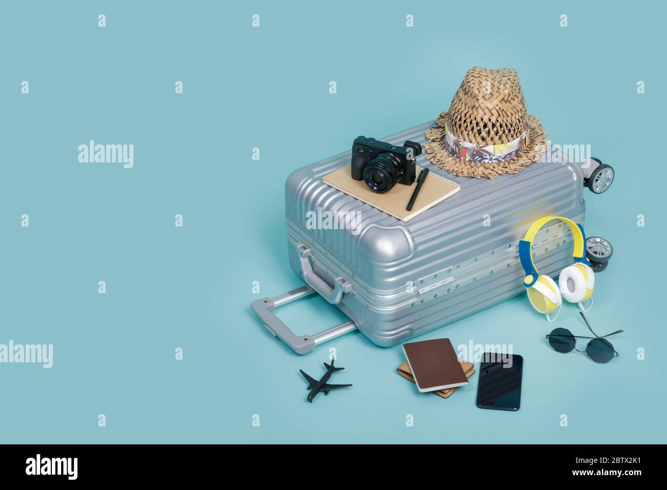 Travel Baggage with passport, camera, hat, wallet, airplane toy and smartphone isolated on blue background with copy space, Travel concept background Stock Photo