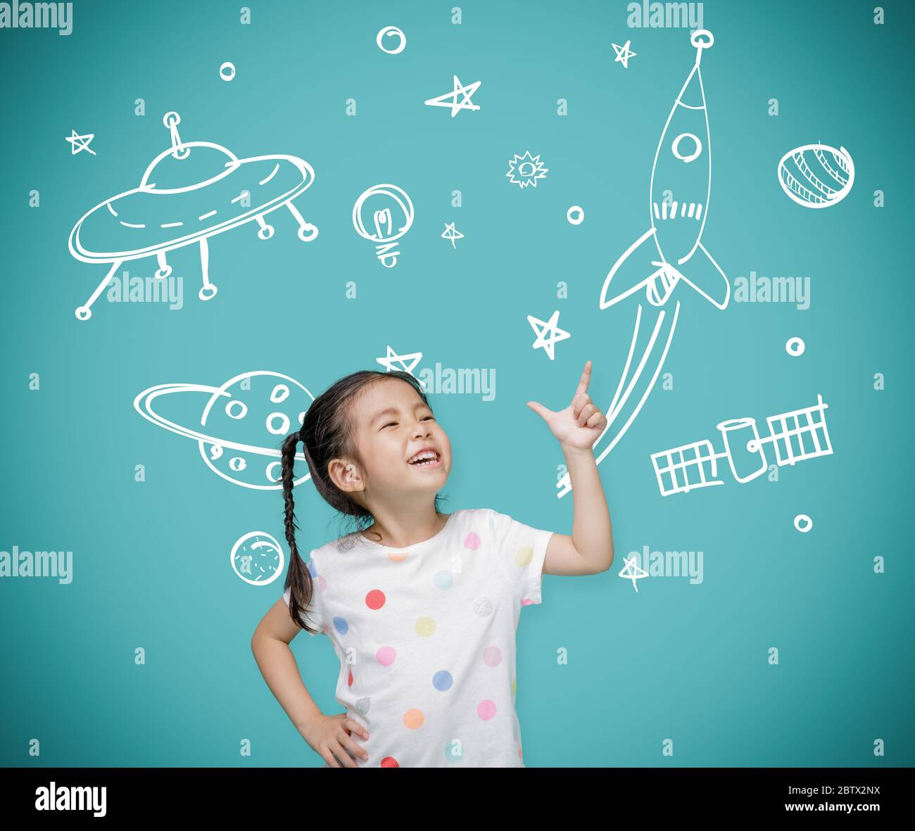 Asian child girl pointing at the blackboard with imagination the astronaut and space rocket, Creative and dreams of childhood concept Stock Photo