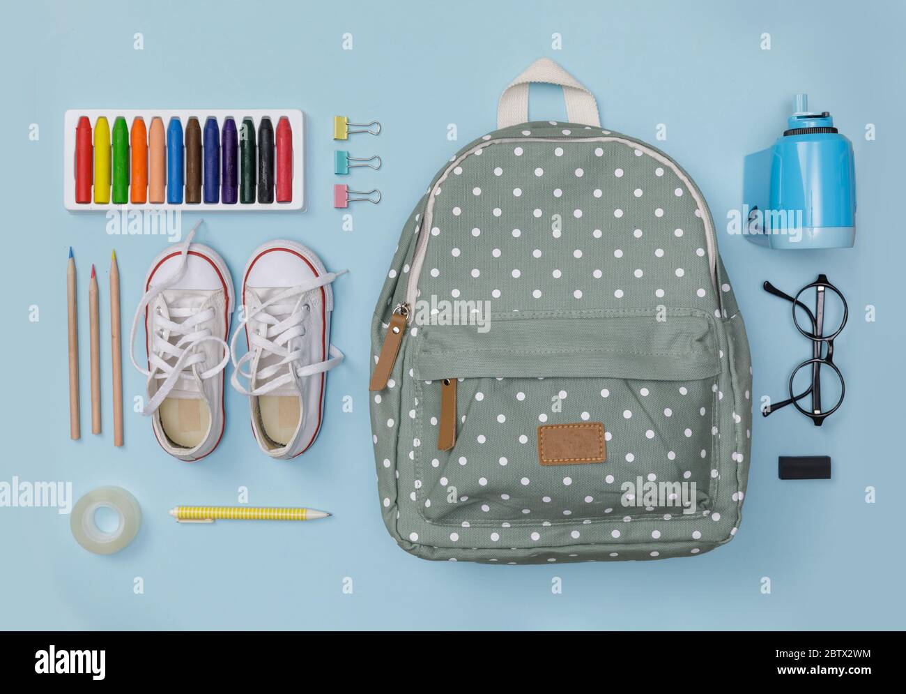Creative flatlay of education blue table with backpack, shoes, colorful crayon, eye glasses, isolated on blue background, Concept of education and bac Stock Photo