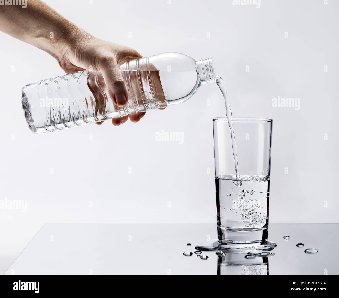 Hand Pouring Fresh Pure Water From Bottle Into A Glass On The Table