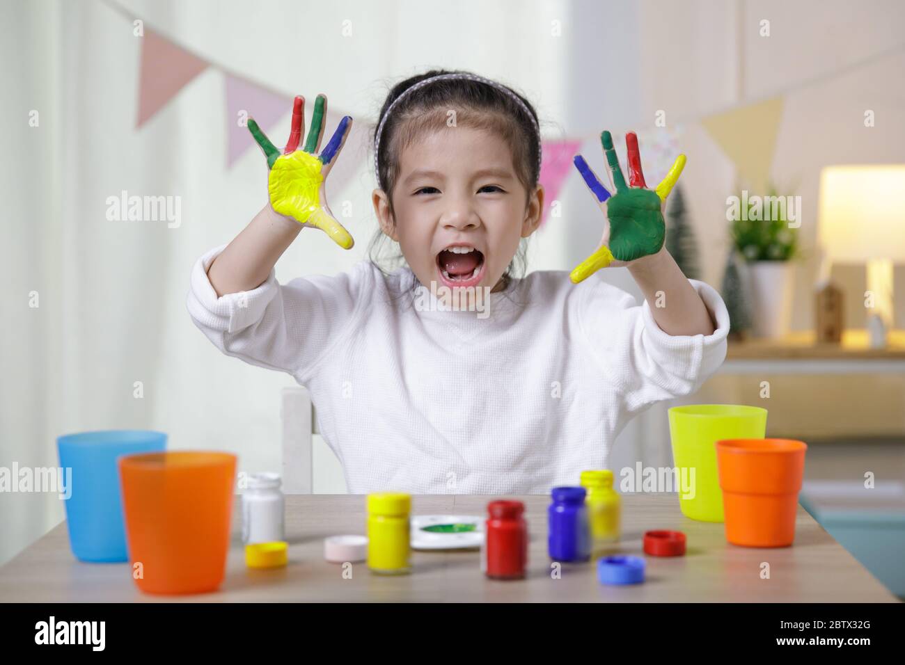 Kid's creativity, Child little asian girl hands painted in colorful paints in the class room at home, Educational concept for school Stock Photo