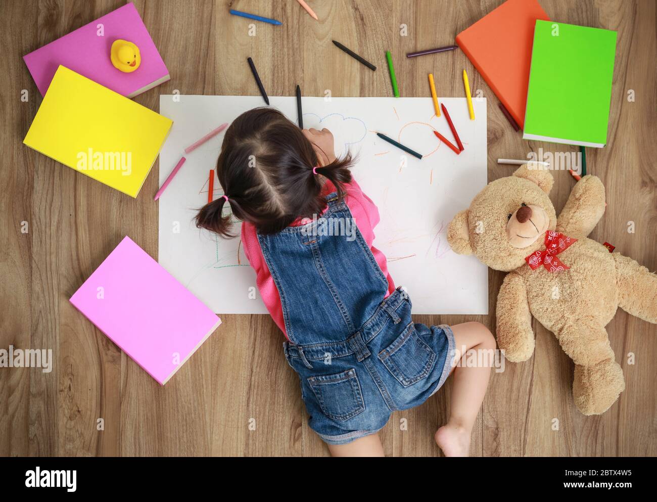 Adorable little girl drawing artwork. Studio shot top view of child on floor Stock Photo