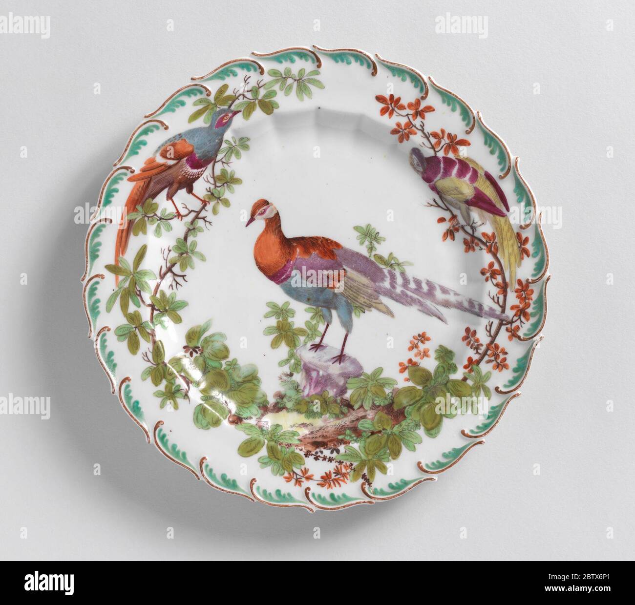 Fruit or Dessert Plate with Disheveled Birds. Research in ProgressScalloped edge with green feather motif. Fluted cavetto. At center, a tropical bird. Stock Photo