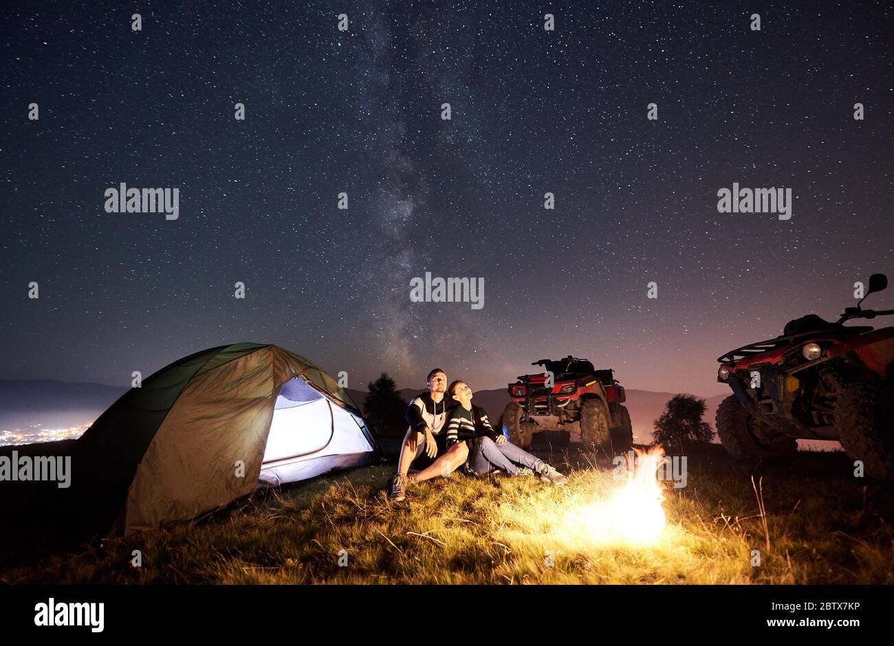 Man and woman sitting together near tourist tent, burning campfire, two ...