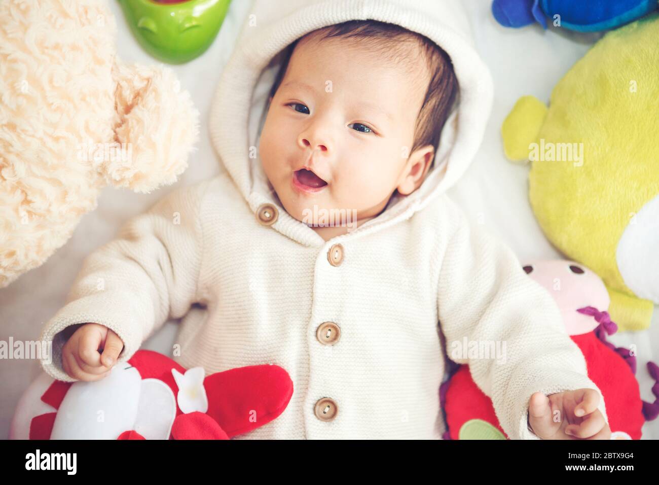 Funny Baby  playing with a beautiful doll - Vibrant color effect Stock Photo