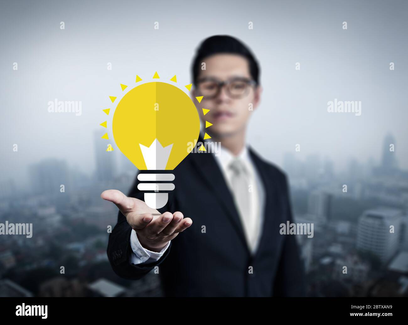 Concept, idea of young businessman with bulb in hand, new business in the city collection, studio shot Stock Photo