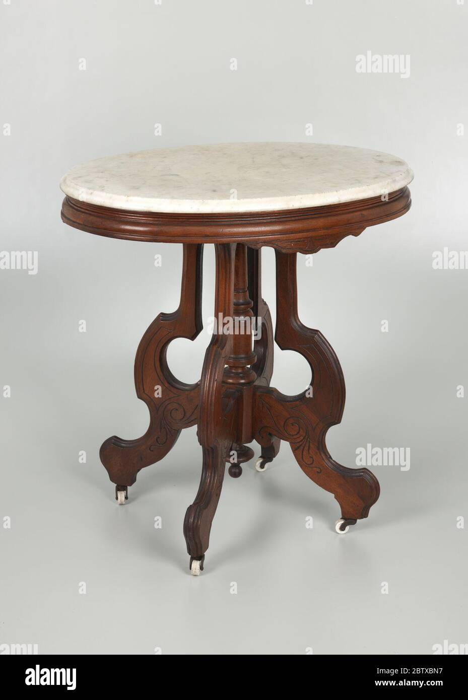 Marbletop table from the home of Robert Smalls. A Victorian Era oval marble-top table made of walnut with a 7/8' thick detachable top resting on an oval-shaped wood frame. The legs are s-formed with a decorative spindle connecting the legs at the bottom portion of the central post. Stock Photo