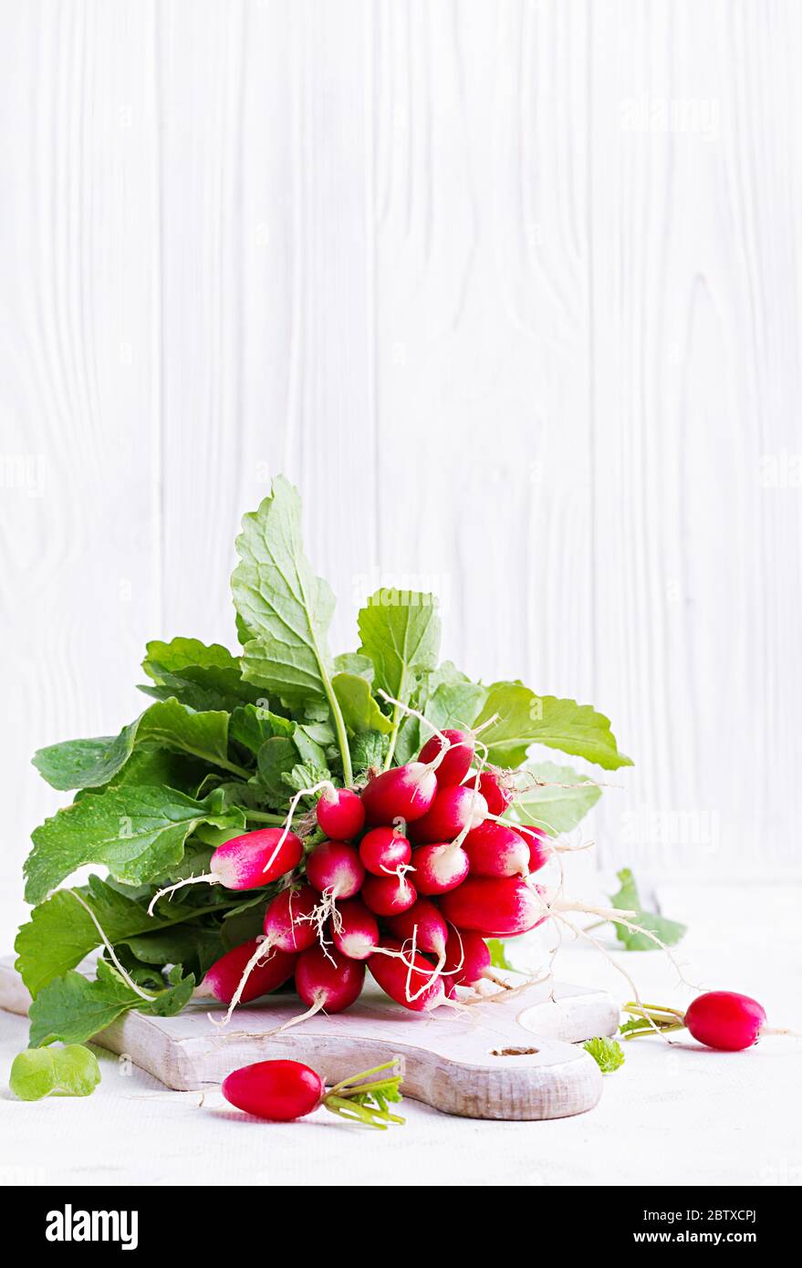 Spring harvest red radish on light background. Bunch of fresh french breakfast radish. Growing vegetables. Vegetarian food. Stock Photo