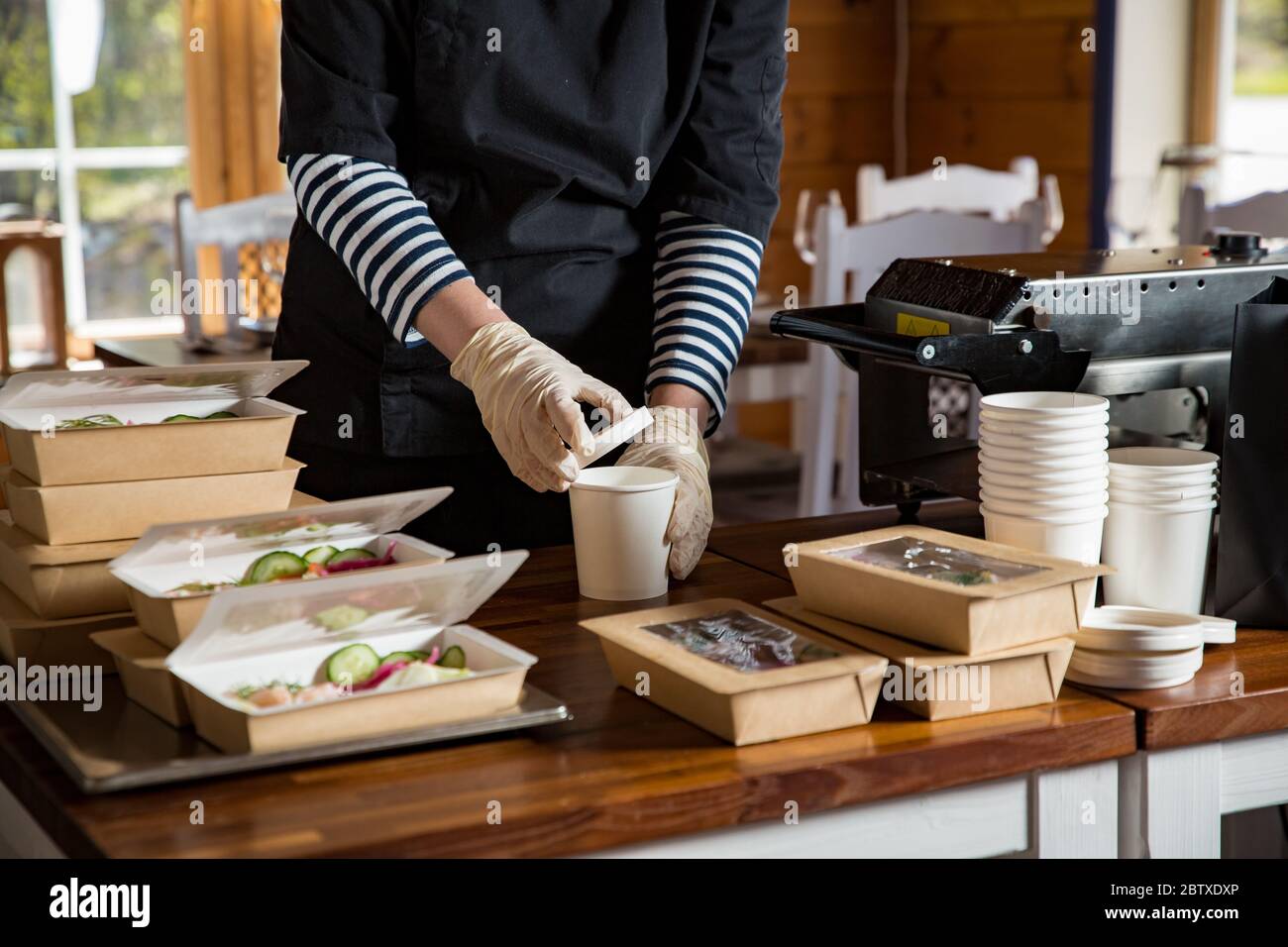 Restaurant worker wearing protective mask and gloves packing food boxed