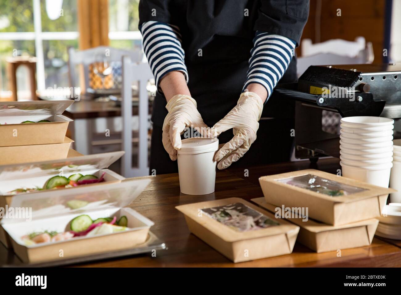 Restaurant worker wearing protective mask and gloves packing food boxed