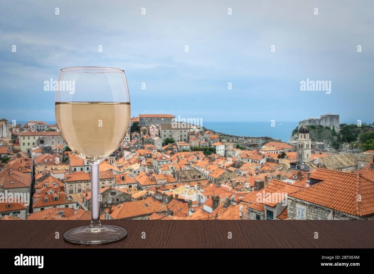 Glass of white wine with view of red rooftops in historic city center