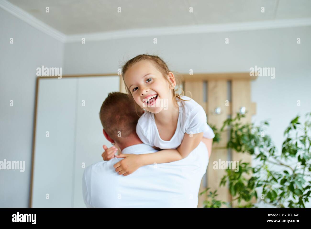 Father and daughter in white spending time at home Stock Photo