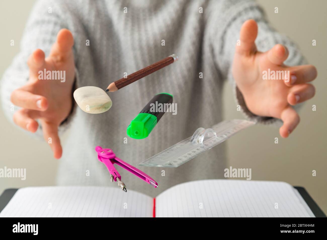 Levitating school supplies for math - notebook, pen, ruler, pencil, divider and eraser levitating between student hands. Concept of education and crea Stock Photo