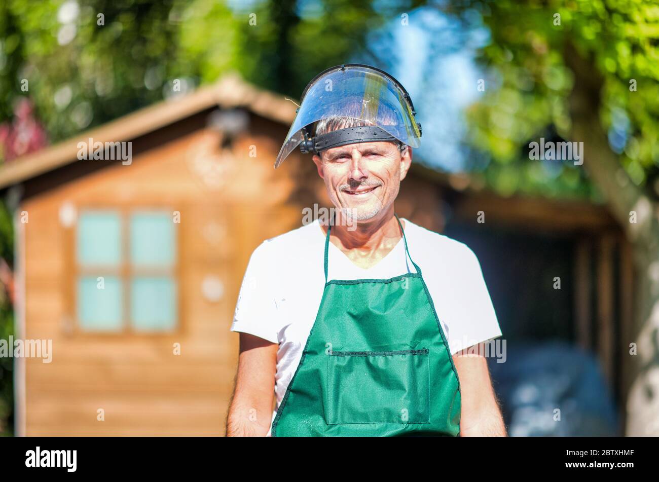 Happy male gardener wearing helmet using lawn mower Stock Photo - Alamy
