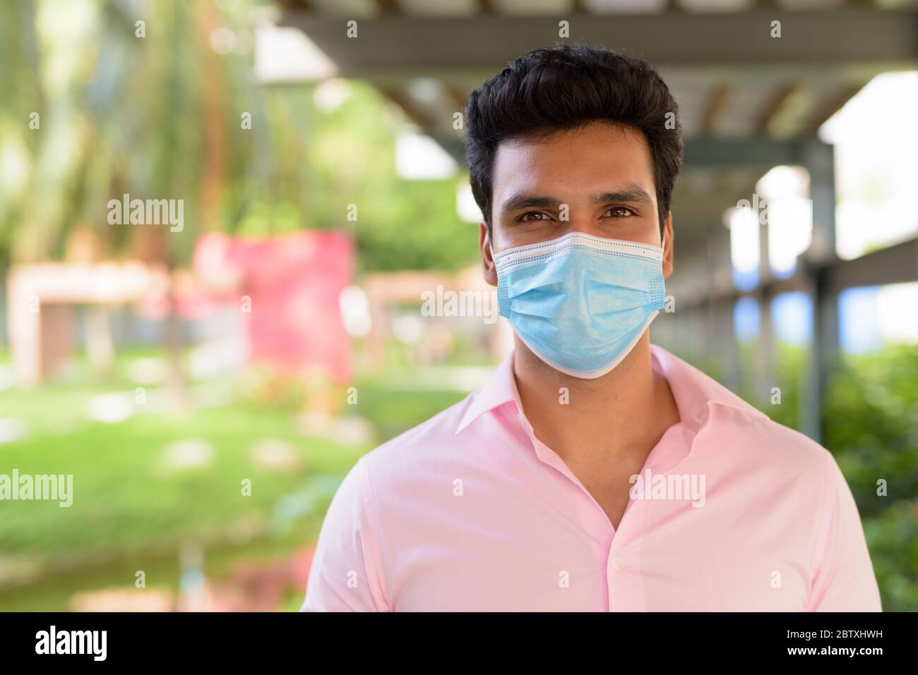 Face of young Indian businessman wearing mask at the park Stock Photo ...
