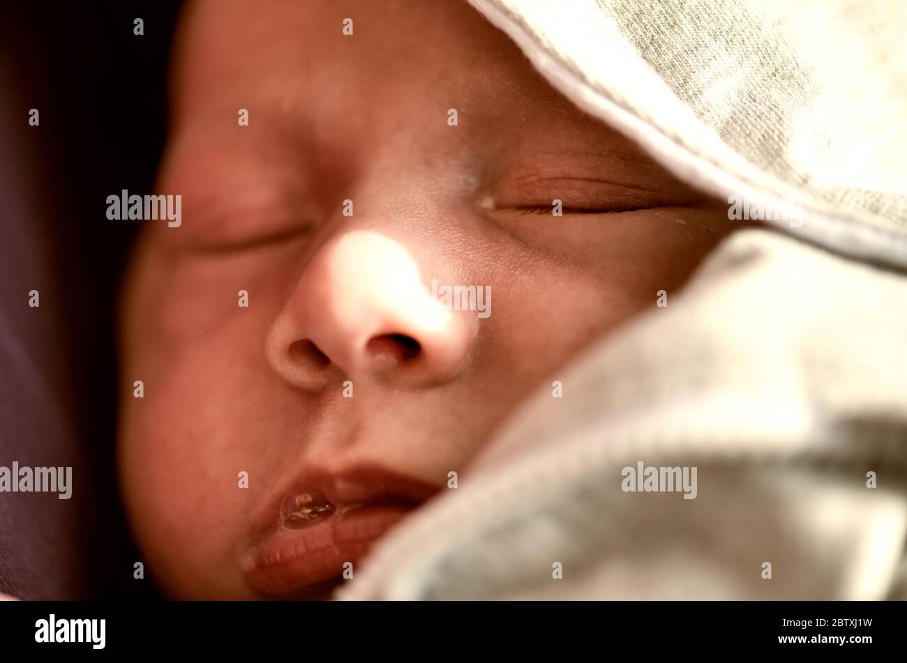 Newborn baby sleeping protected by hood. Stock Photo