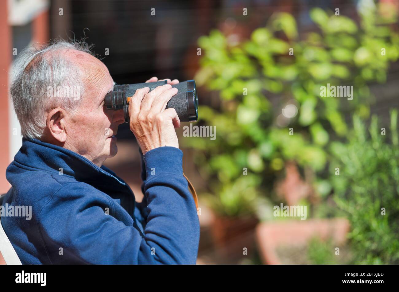 Elderly man holding binoculars looking in the distance Stock Photo Alamy