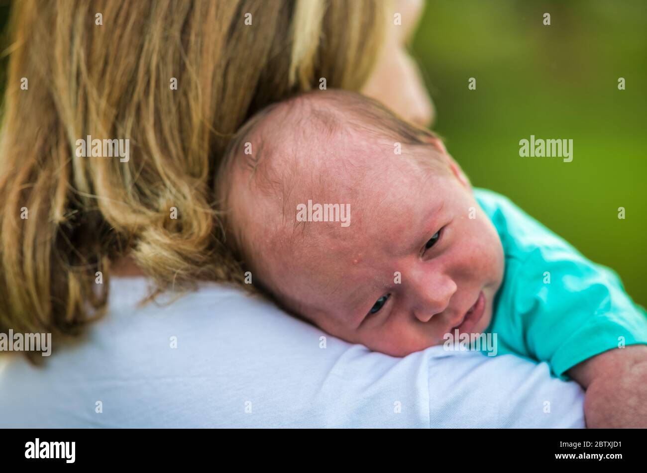 Newborn baby outdoor in the city park with his mather taking care of