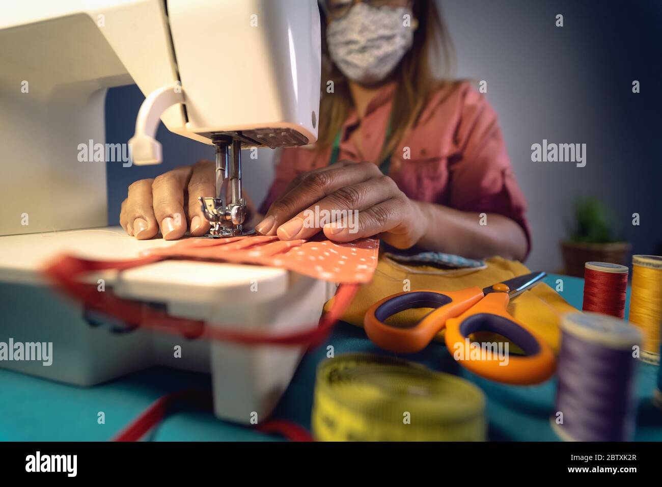 Close up Latin female hands sewing with sew machine homemade medical face mask for preventing and stop corona virus spreading Stock Photo