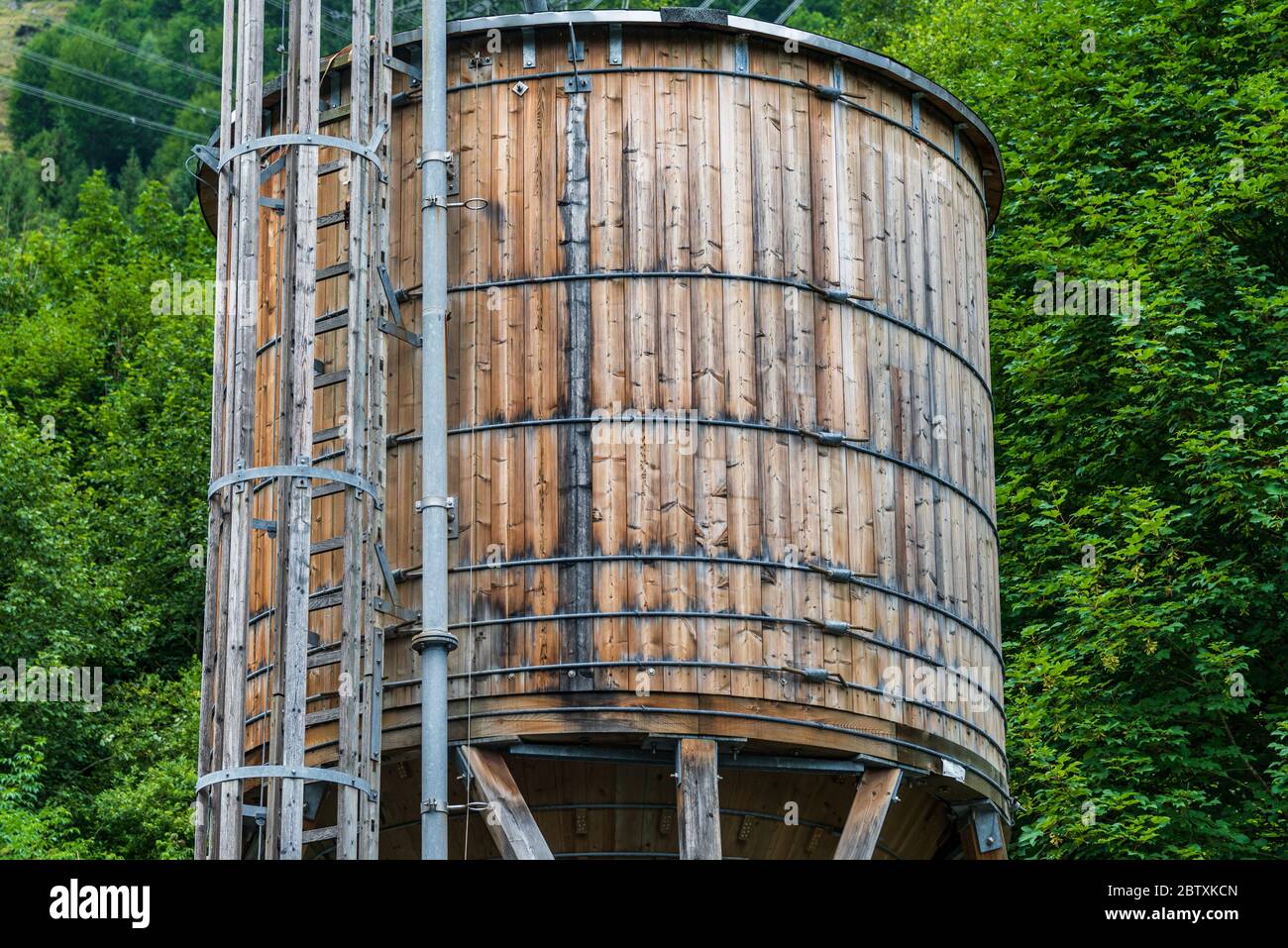 The wooden water supply tank on the background of green trees. The tank ...