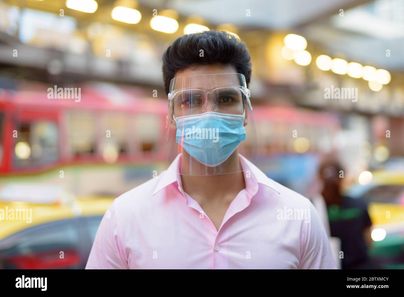 Face of young Indian businessman with mask and face shield in the city ...