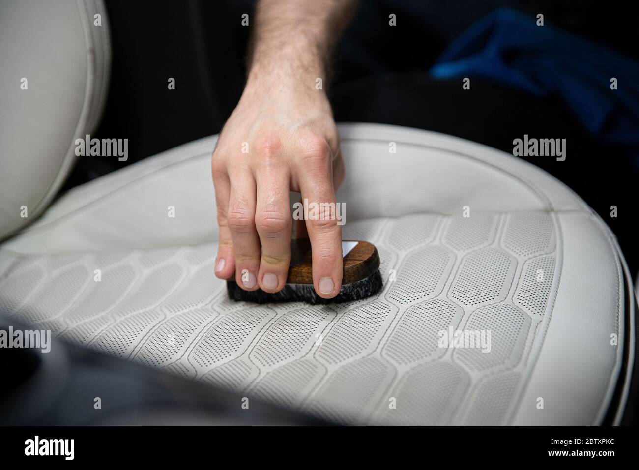 Car wash worker cleaning leather car seat with brush. Car detailing