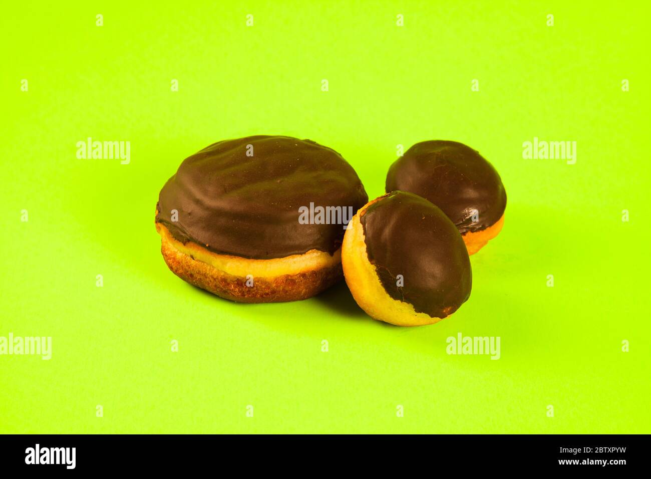 Boston cream donut large and small on green background Stock Photo